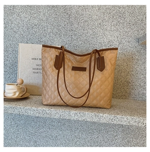 Close-up of brown quilted tote bag showing diamond stitch texture and leather logo detail