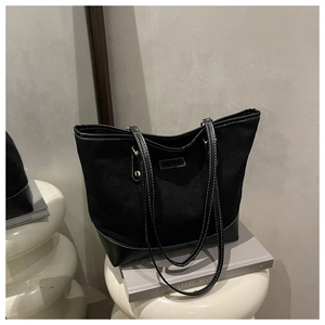 Detail of minimalist black tote bag featuring contrast white stitching and leather trim