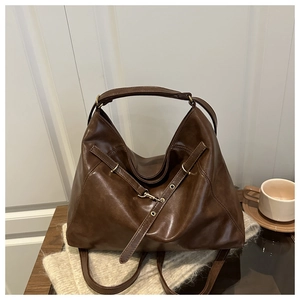 Detail of dark brown tote bag with metal eyelets and vintage gold hardware on a sweater