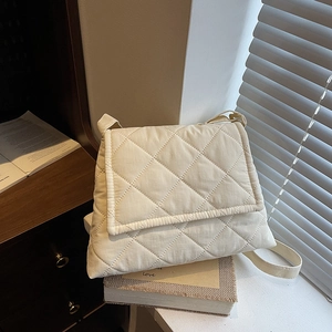 Chic quilted rhombic crossbody bag in off-white with wide shoulder strap on books