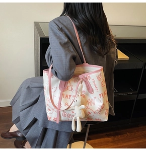 Detail of graffiti canvas tote with pink trim and white plush bunny pendant