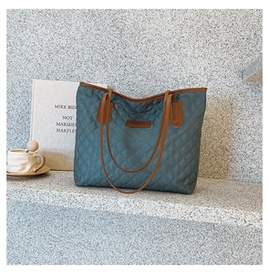 Detailed view of Morandi blue quilted tote bag with brown leather handles and logo patch