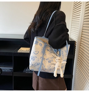 Detail of canvas tote bag showing blue graffiti prints and white plush bunny pendant