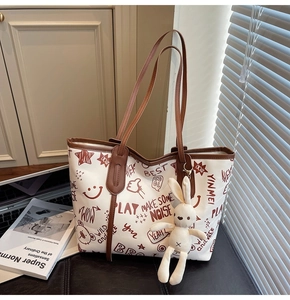 Detail of white tote bag with red doodle print and cute beige rabbit plush charm