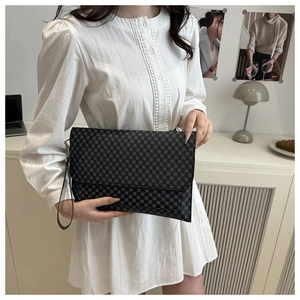 Detailed shot of grey checkered envelope wristlet held against white lace dress