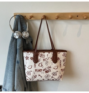 Detail of canvas tote bag with brown leather handles and graffiti print on wall hook