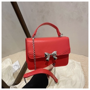 Detail of red mini square bag featuring silver bow buckle and elegant metal chain strap