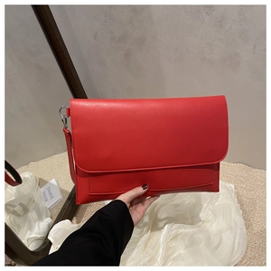 Detail of red leather envelope clutch bag with metal D-ring and crossbody strap