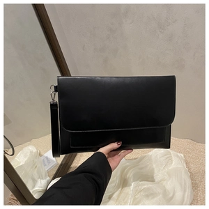 Detail of black minimalist envelope clutch bag with silver metal hook and wrist strap