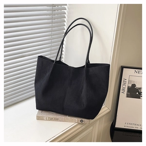 Close-up of matte black tote bag texture with slender straps in minimalist interior