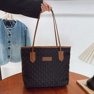 Quilted black nylon tote bag with brown leather straps and spacious interior for daily use