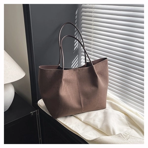 Macro detail of dark brown suede tote bag showing premium matte texture and vertical stitching
