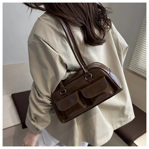 Model wearing a deep brown retro shoulder bag with glossy leather and flap pockets