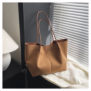 Close-up of brown suede tote bag texture with minimalist stitching and dual straps