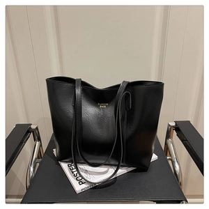 Détail du cabas en similicuir noir avec inscription dorée posé sur une chaise chic