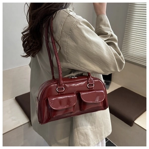 Detail of dark red glossy shoulder bag featuring retro double front pockets and slim straps