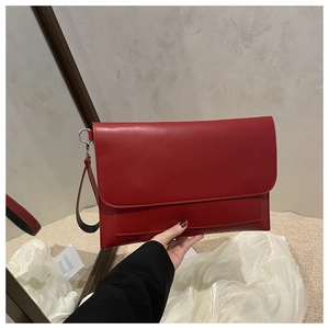 Macro detail of red matte leather clutch bag with envelope flap and wristlet strap