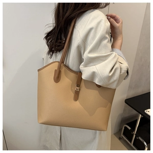Detail of light brown tote bag featuring lychee texture leather and gold buckle strap