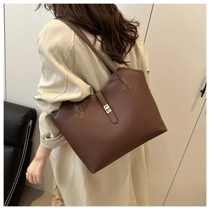 Detail of dark brown leather tote bag with gold lock and litchi grain texture