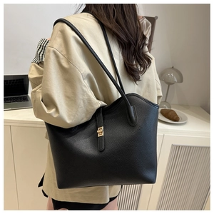 Detail of black pebbled leather tote with golden buckle shown in a lifestyle setting