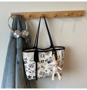 Close-up of a white graffiti tote bag with a cute plush rabbit charm on a wall hook