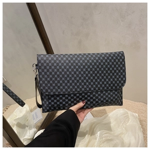 Detail of navy geometric pattern on a stylish leather clutch with carry strap