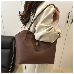 Detailed side view of brown lychee grain leather tote bag with gold metal twist lock