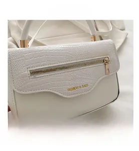 Détail du sac à main blanc crème avec rabat motif crocodile et accents dorés zippés
