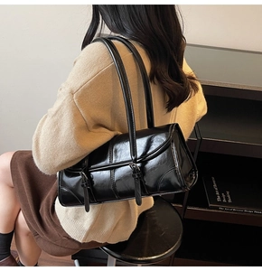 Glossy black baguette shoulder bag shown on model with minimalist modern aesthetic