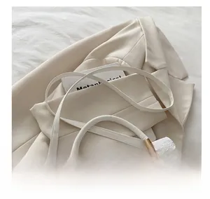 Gros plan du sac blanc texture crocodile avec double fermeture éclair sur beige