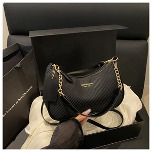 Close-up of black textured shoulder bag with gold chain and chic gift box packaging