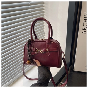 Detail of burgundy shell bag featuring gold horsebit and stylish tassel charm detail