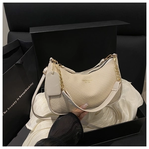 Detail of cream woven crescent bag with gold chain strap in high-end gift box packaging
