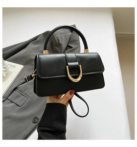 Detail of minimalist black leather handbag with premium gold D-ring buckle and handle