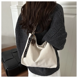Macro detail of creamy faux suede tote bag with gold magnetic buckle and woven rope strap
