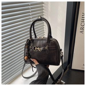Detail view of brown shell crossbody bag with golden horsebit and dual zipper closure
