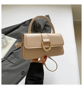 Detail of elegant beige crossbody bag with gold U-shaped buckle and textured leather