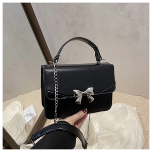 Gros plan détaillé du mini sac noir avec nœud en métal argenté et bandoulière chaîne