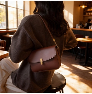 Close-up of a brown leather shoulder bag with a gold rectangular metal lock clasp