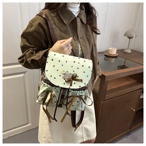 Detail of mint green school backpack featuring star prints and brown ribbon bow tie