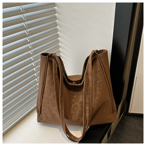 Detail showing the dark brown tote bag with subtle leopard texture and dual shoulder straps