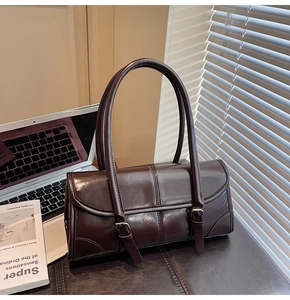 Close-up of deep coffee oil wax leather texture and dual buckle detail on shoulder bag