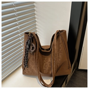 Detail of dark brown leopard pattern tote bag with tassel charm in soft window light