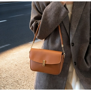 Detail of caramel leather shoulder bag with gold square clasp and chain strap