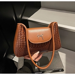Close-up of brown crocodile texture shoulder bag with silver metal bow detail