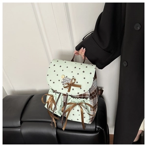 Detail of mint green star backpack with plaid panels and decorative brown ribbon bow