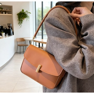Detail of caramel rectangle shoulder bag with gold metal buckle and chain strap
