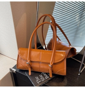 Detail of orange baguette bag with glossy leather finish and twin buckle straps