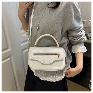 Détail de la texture crocodile blanche et lettrage doré sur le sac pour femme