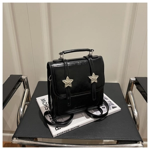 Détail d'un sac à dos noir brillant avec deux boucles métalliques en forme d'étoile argentée